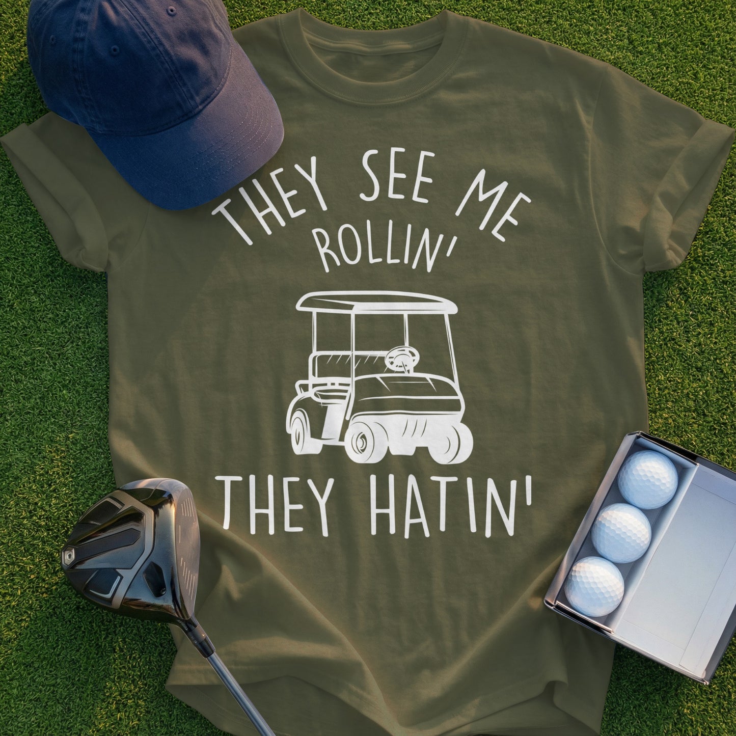 Olive t-shirt with white graphic: "They See Me Rollin' They Hatin'" and a golf cart.