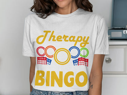 White t-shirt with "Therapy" and "BINGO" in colorful text, with bingo card graphics.