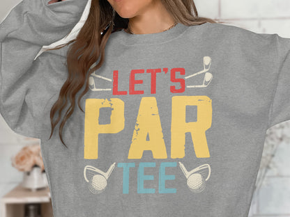 Grey sweatshirt with "Let's Par Tee" text and golf club and ball graphics.