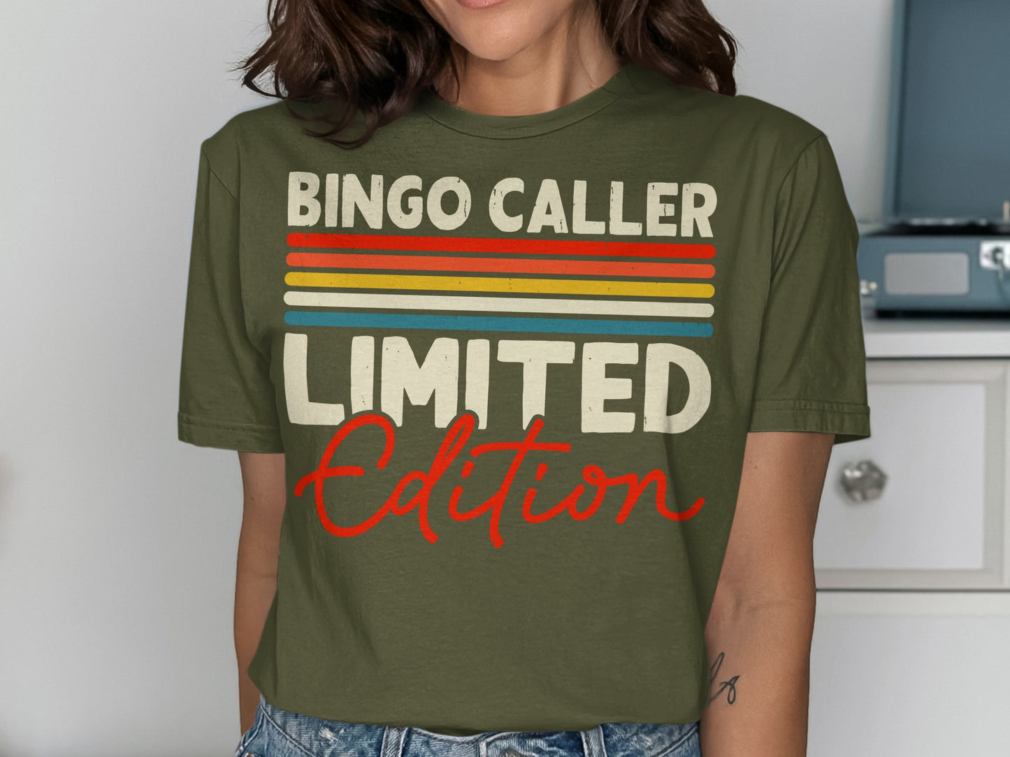 Olive green t-shirt with "Bingo Caller Limited Edition" text in colorful stripes and red script.
