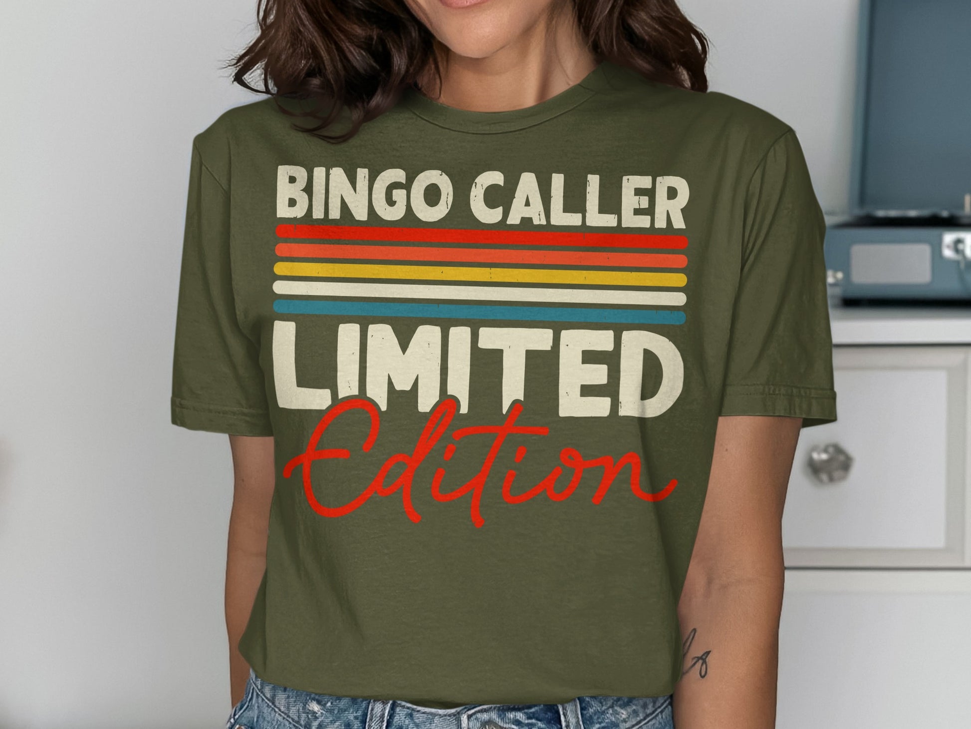 Olive green t-shirt with "Bingo Caller Limited Edition" text in colorful stripes and red script.