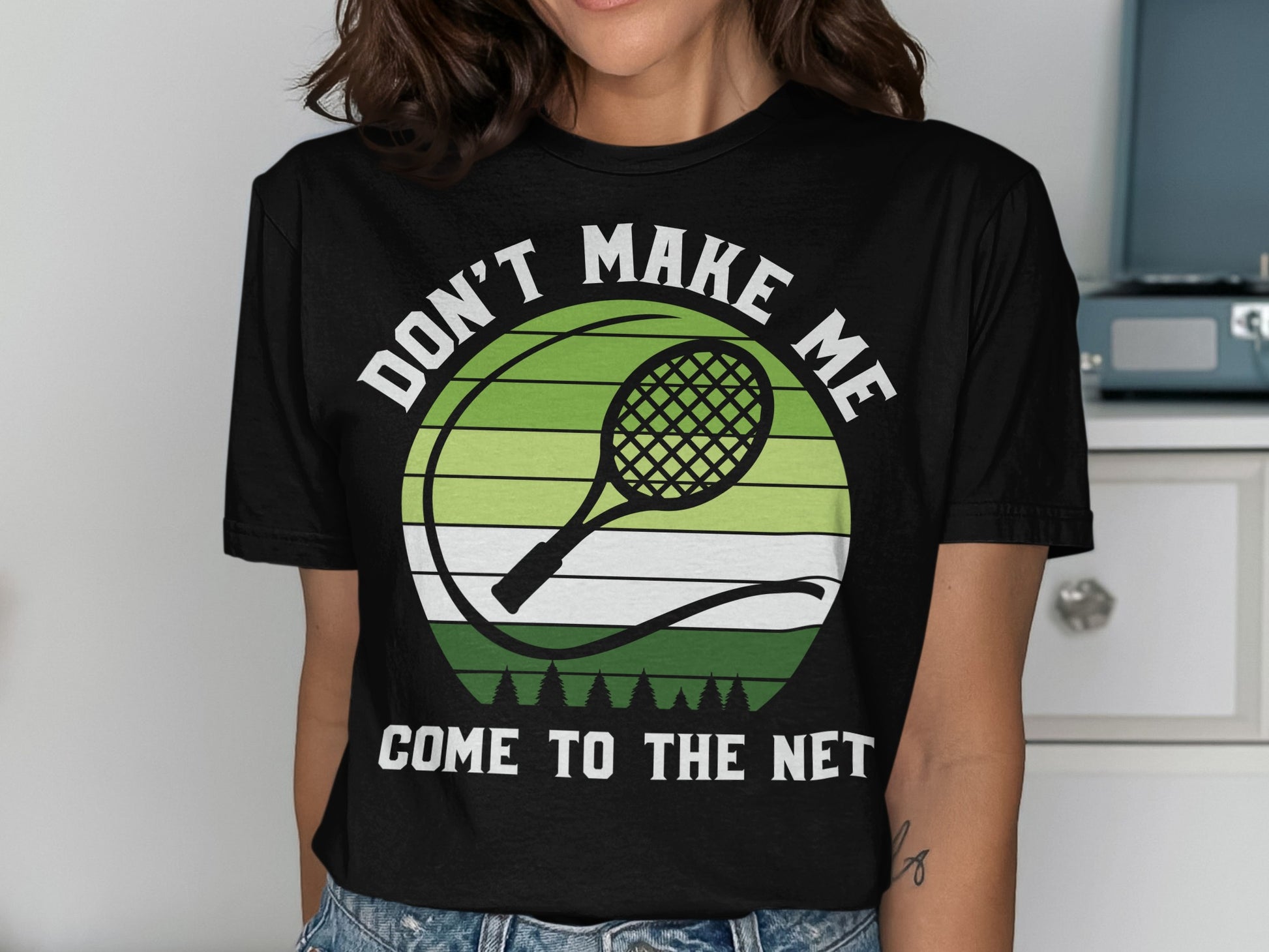 Black t-shirt with white text "DON'T MAKE ME COME TO THE NET" and tennis racket graphic.