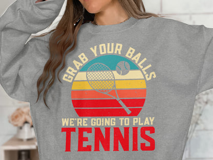 Grey sweatshirt with "GRAB YOUR BALLS WE'RE GOING TO PLAY TENNIS" text and tennis graphic.