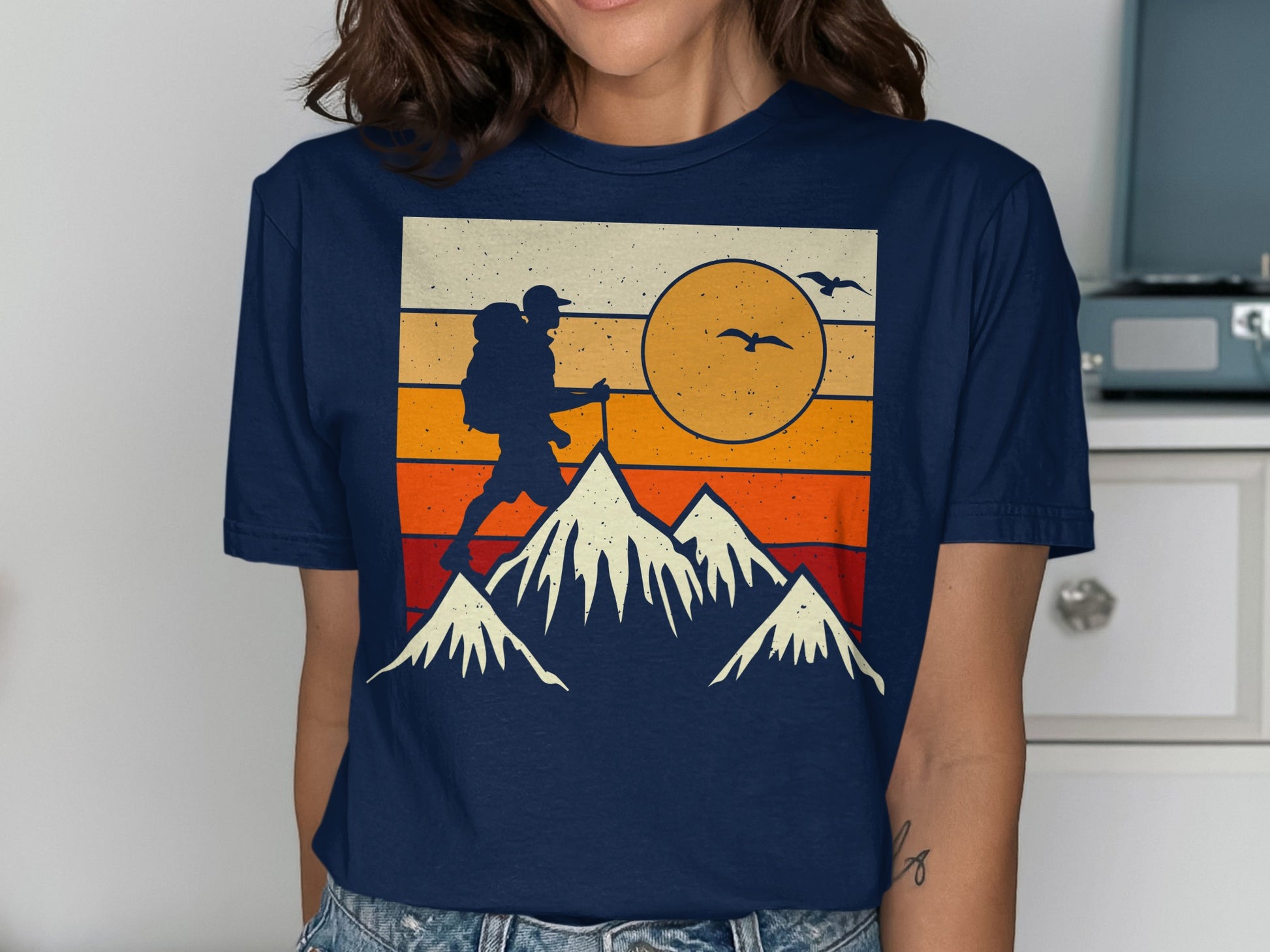 Retro sunset graphic of a hiker and mountains on a navy t-shirt.