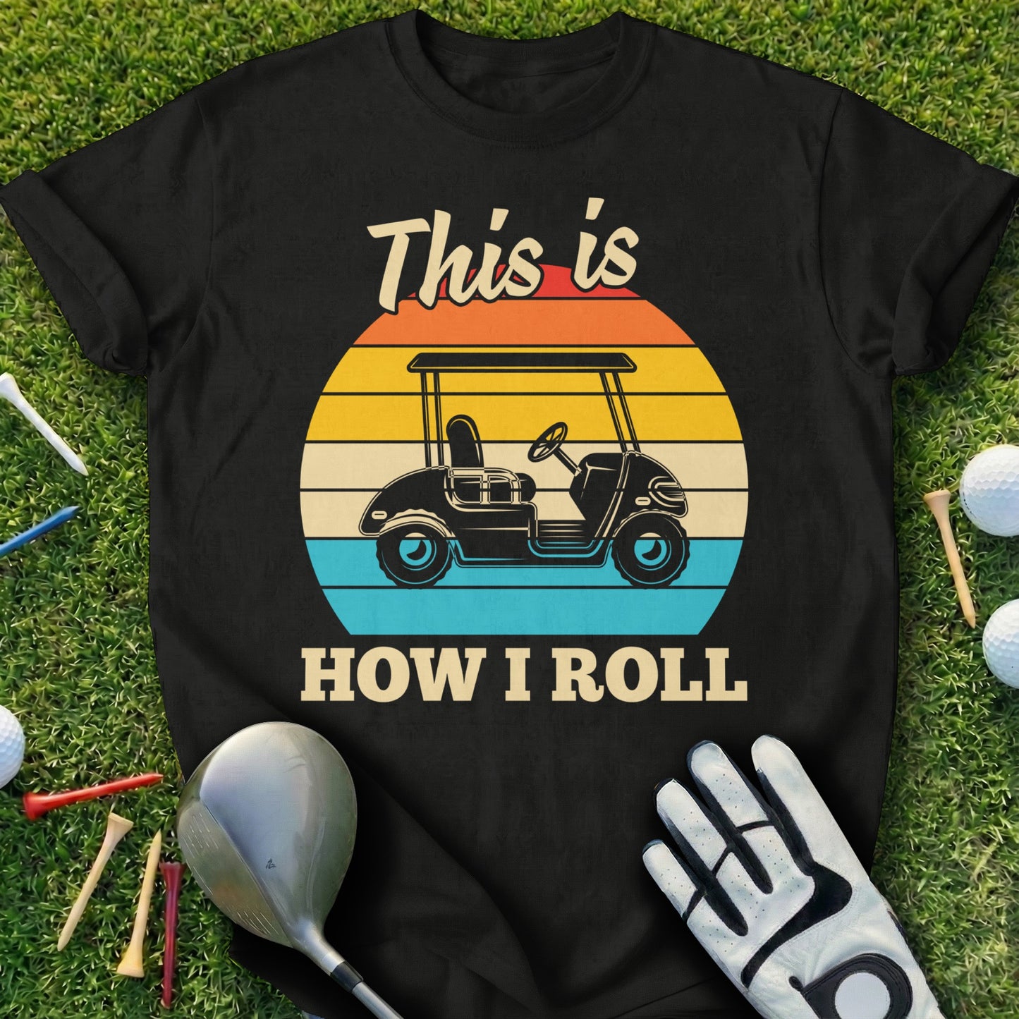 Black t-shirt with a graphic of a golf cart and text "This is HOW I ROLL" on a sunset background.