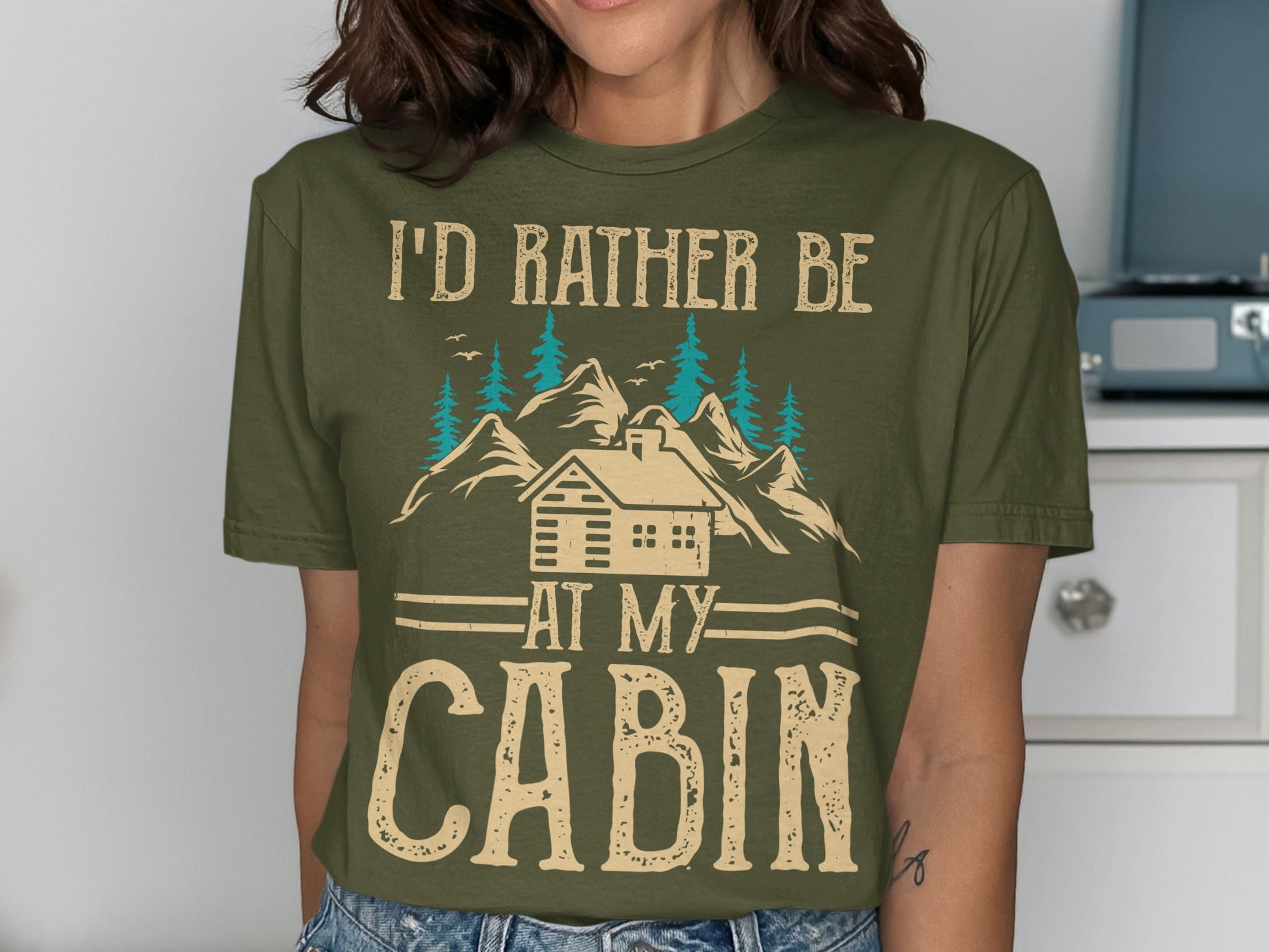 Green t-shirt with "I'd rather be at my cabin" text and mountain graphic.