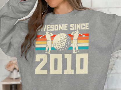 Gray sweatshirt with "Awesome Since 2010" and golf graphic.