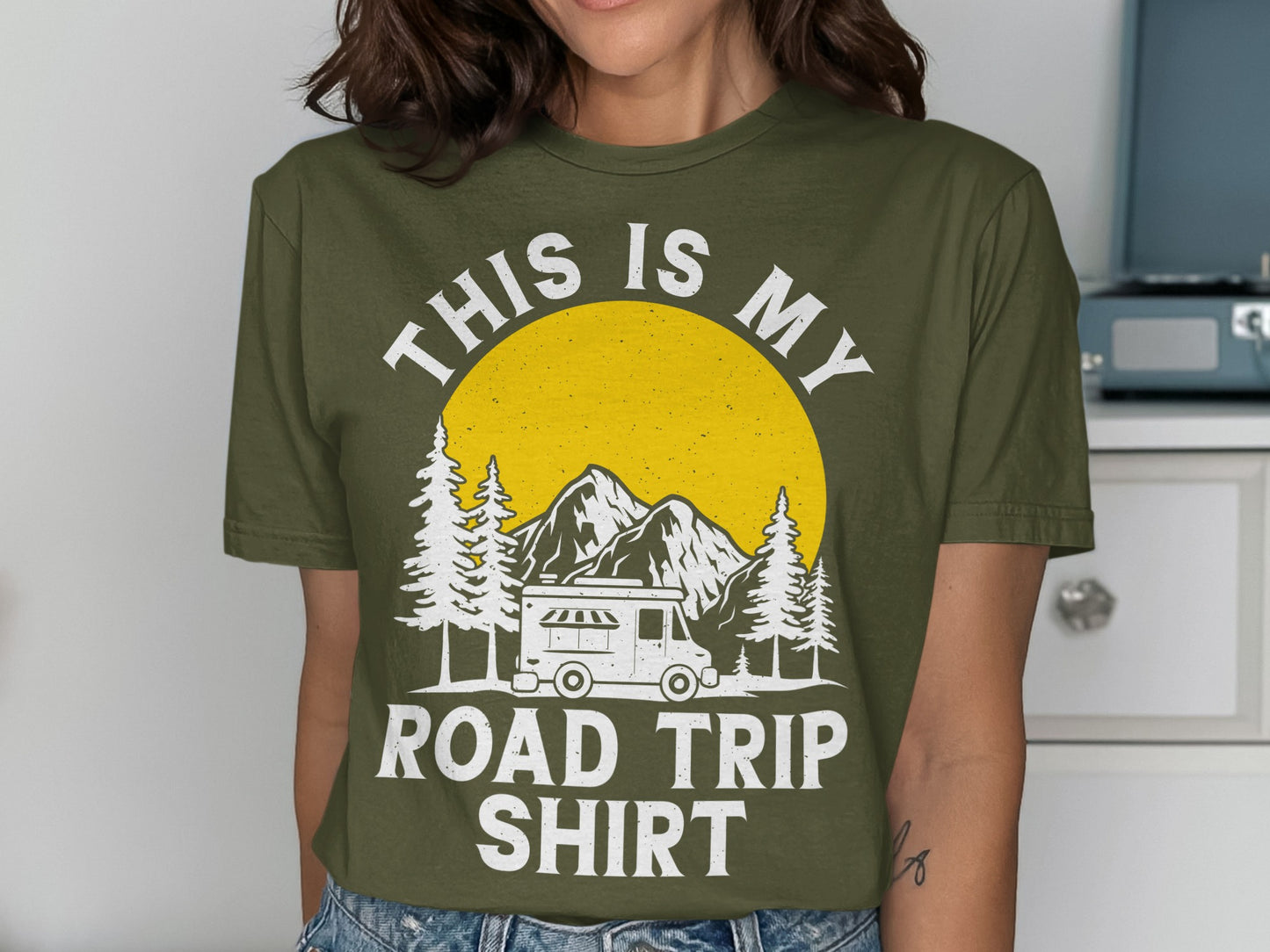 Olive green t-shirt with "THIS IS MY ROAD TRIP SHIRT" text and a camping scene.